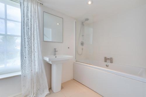a white bathroom with a sink and a tub and a shower at 4 Bed in Wangford oc-2tov in Wangford