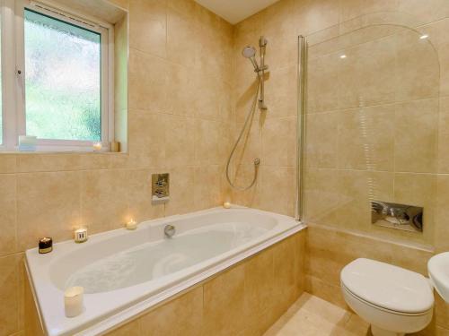 a bathroom with a tub and a toilet and a window at 3 Bed in Keswick oc-90266 in Applethwaite