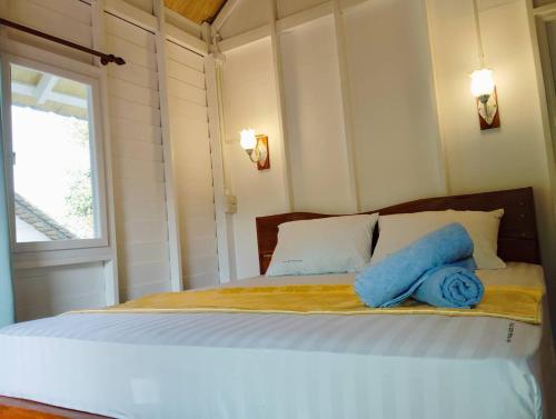 a bedroom with a bed with two blue towels on it at Koh Phaluai beach cottage in Koh Phaluai