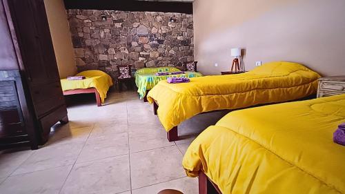 a room with three beds with yellow sheets at Cabaña Aklla in Tilcara