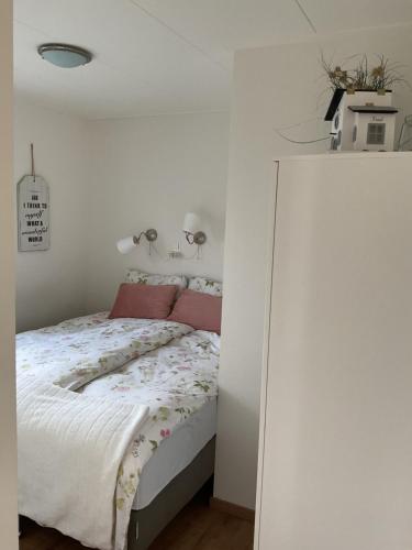a white bedroom with a bed with pink pillows at B&B De Singel in Medemblik