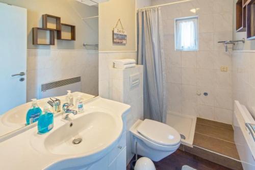 a white bathroom with a sink and a toilet at Ferienhaus-Mackeriege in Norden