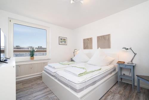 a white bedroom with a bed and a window at Solymar Whg 64 in Grömitz
