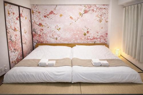 a bedroom with a large bed with two towels on it at Camelot Home in Fukuoka