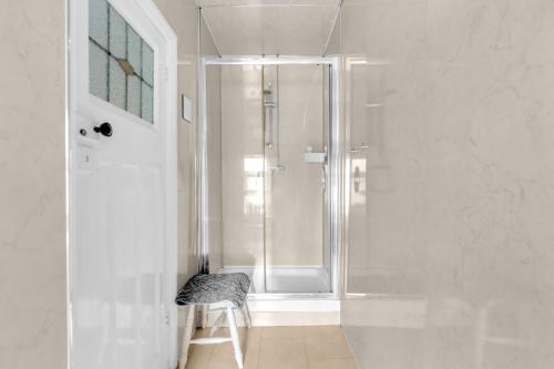 a white bathroom with a shower and a stool at Mallowview guest house in Cleethorpes