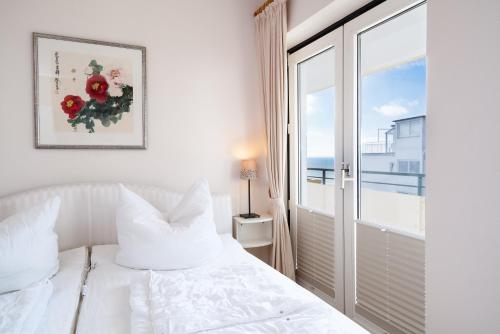 a bedroom with a white bed and a large window at Miramar Whg 513 in Grömitz