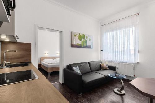 a living room with a black couch and a kitchen at Solymar Whg 11 in Grömitz