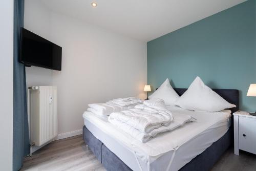 a bedroom with a bed with white sheets and a flat screen tv at Commodore Whg 15 in Grömitz