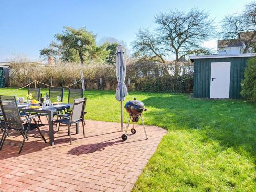 a patio with a table with a grill and an umbrella at Ferienhaus Kranichnest in Breege