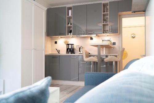 a kitchen with grey cabinets and chairs in a room at Solymar Whg 29 in Grömitz