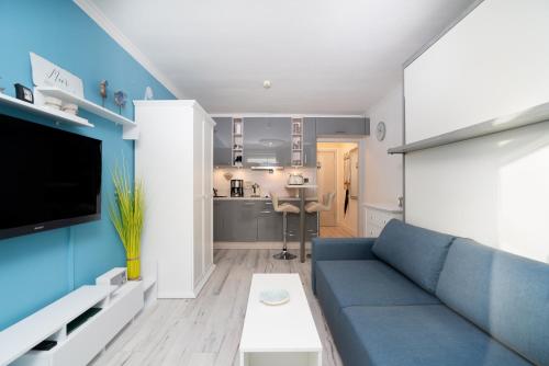 a living room with a blue couch and a kitchen at Solymar Whg 29 in Grömitz