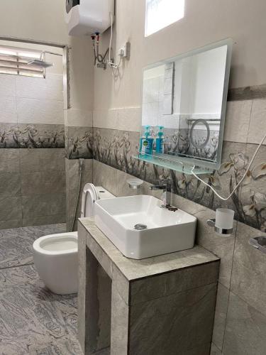 a bathroom with a sink and a toilet and a mirror at Horizon in Katunayaka