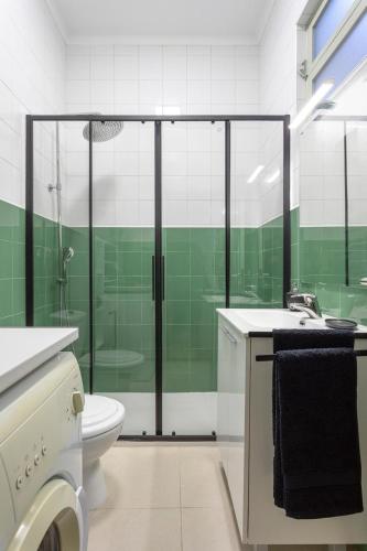 a green and white bathroom with a toilet and a shower at Casa em bairro típico de Aveiro in Aveiro