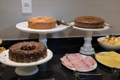 a table with three tiers of cakes on plates at Hotel Vila Verde in Penápolis