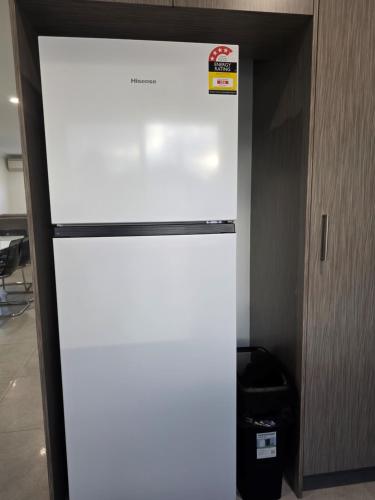 a white refrigerator sitting inside of a room at Cozy Retreat - 3 Bedroom House in Perth