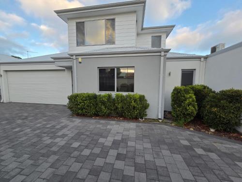 a white house with a driveway at Cozy Retreat - 3 Bedroom House in Perth