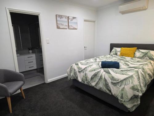 a bedroom with a bed and a chair and a window at Cozy Retreat - 3 Bedroom House in Perth