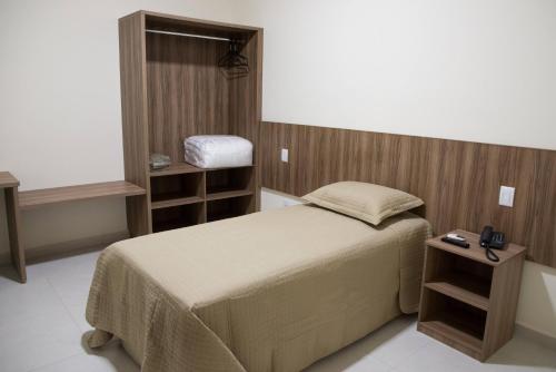 a small bedroom with a bed and a table at Hotel Vila Verde in Penápolis