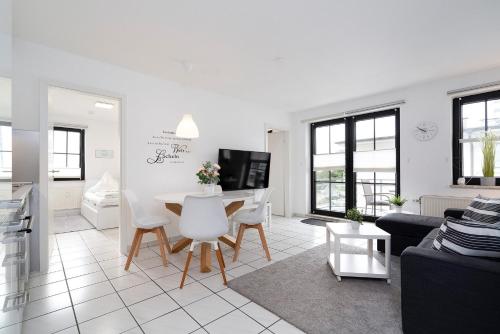a white living room with a table and chairs at Titania Whg 10 in Grömitz