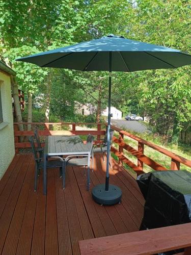 a table and chair under an umbrella on a deck at Casa Gaumaise & Casa Cool in Virton