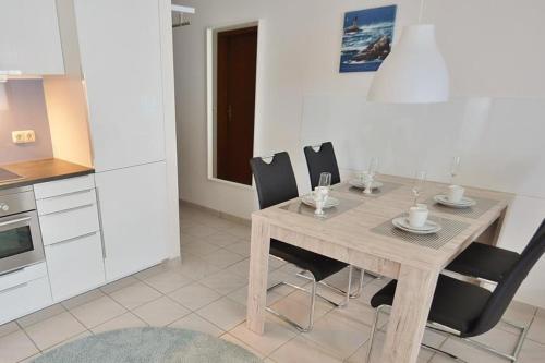 a kitchen with a wooden table and black chairs at Titania Whg 7 in Grömitz