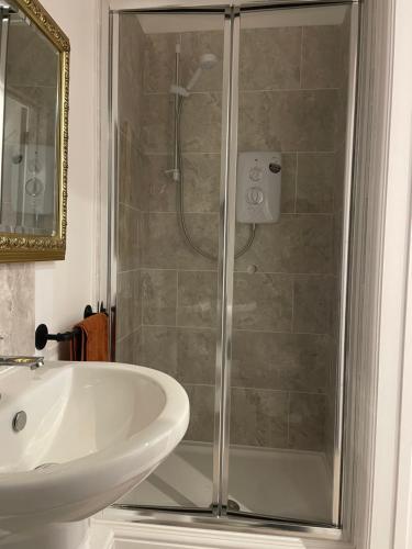 a shower with a glass door next to a sink and a toilet at Weymouths Coastal Nook in Weymouth