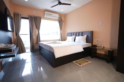 a bedroom with a bed and a large window at Hotel SagarPriya in Digha