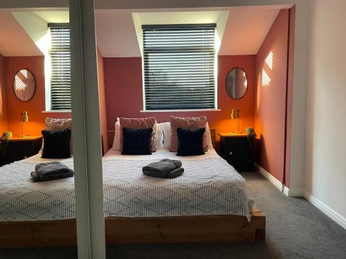two beds in a bedroom with orange walls and mirrors at Cosy Chester Casa - free parking in Chester