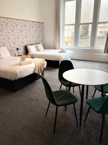 a room with two beds and a table and chairs at Piccolo in Glasgow