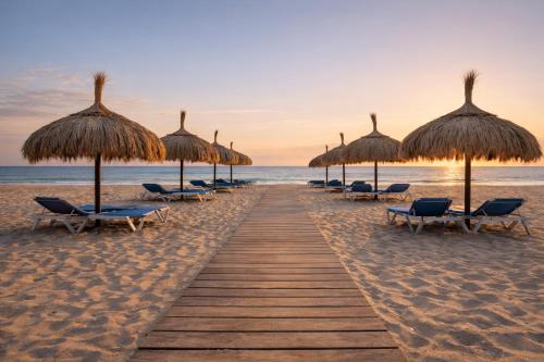 a row of straw umbrellas and chairs on the beach at Herdade dos Salgados in Guia