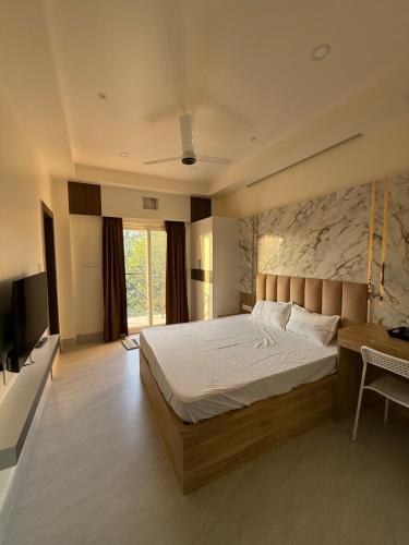a bedroom with a bed and a desk and a television at Xsquare Hotel in Garubhāsa