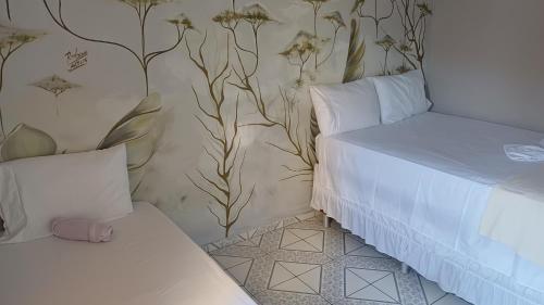 a bedroom with a bed and a wall with flowers at Quarto Aconchego Nordestino in Aracaju