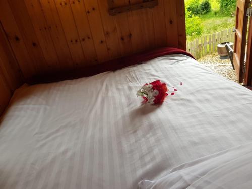 a white bed with a bouquet of flowers on it at Beavers Lodge on top of the Shropshire hills in Craven Arms