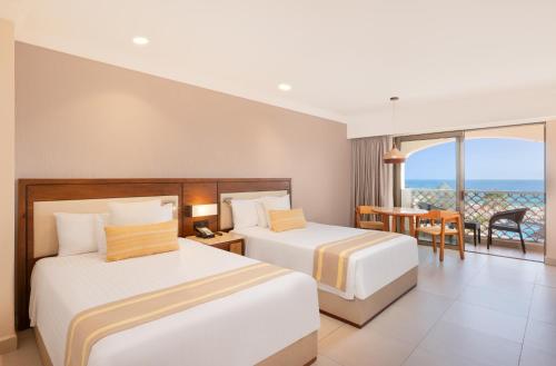 two beds in a hotel room with a balcony at Royal Solaris Los Cabos - All Inclusive in San José del Cabo