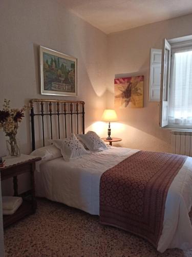a bedroom with a bed and a lamp and a window at Canto del DORMILERO in San Cristóbal de la Vega