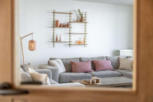 a living room with a gray couch with pink pillows at Hello Zeeland - Port Scaldis 11-031 in Breskens