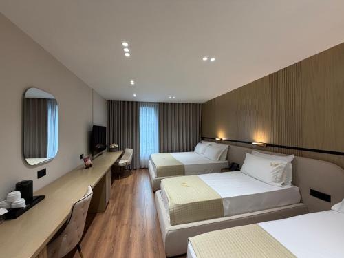 a hotel room with two beds and a mirror at Rich Hotel in Pogradec