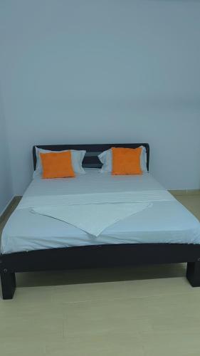 a bed with orange pillows on it in a room at NyaliHomes in Mombasa