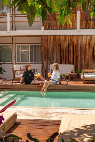 two people sitting on the edge of a swimming pool at AGAM Hotel Boutique Bacalar - Adults Only in Bacalar