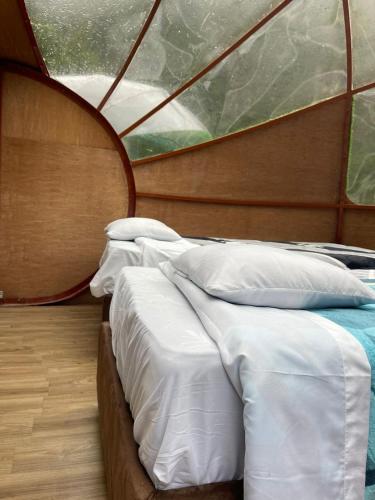two beds in a boat with a window at Chaullay Star Domes in Colcapampa