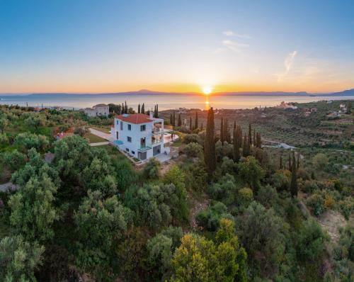 a house on a hill with the sunset in the background at Villa Sadova Private pool Panoramic view in Kalamata