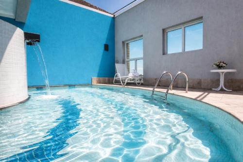 a large swimming pool with a blue wall at Flat em Perdizes, perto da PUC e Allianz Parque in São Paulo