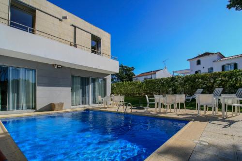 a swimming pool in front of a house at Pé na Areia - Guest House in Vila Real de Santo António