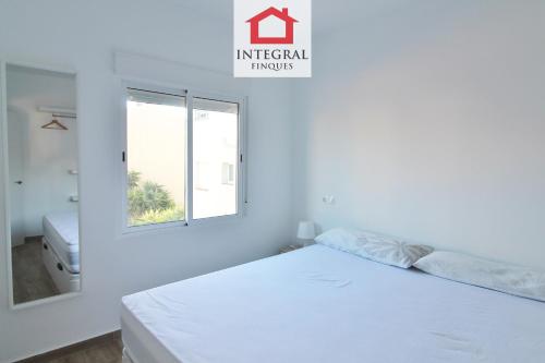 a white bedroom with a bed and a window at Apartament Marea Alta in San Juan de Palamós