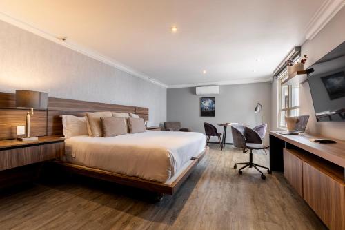 a bedroom with a bed and a desk and a table at Capitalia Obelisk Polanco in Mexico City