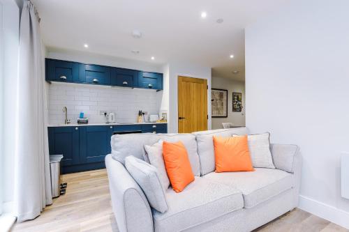 a living room with a white couch with orange pillows at Rock Mill - Superior Apartment with Private Patio in Stony Middleton