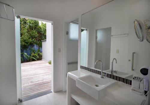 a white bathroom with a sink and a mirror at Villa dos Graffitis Pousada in Morro de São Paulo