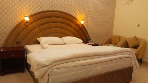 a bedroom with a large bed and a chair at Royalz Hotel in Lahore
