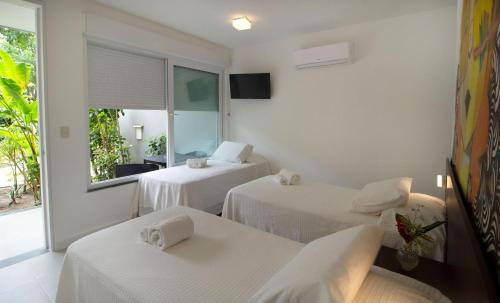 a white room with two beds and a window at Villa dos Graffitis Pousada in Morro de São Paulo