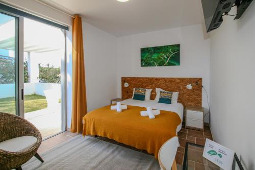 a bedroom with a bed and a large window at Pé na Areia - Guest House in Vila Real de Santo António